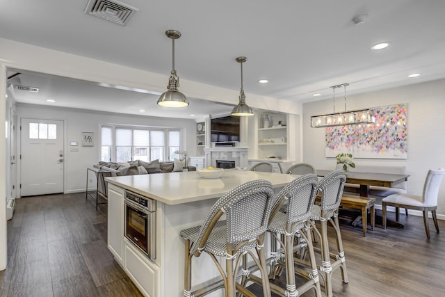 kitchen featuring dark wood finished floors, light countertops, visible vents, and oven