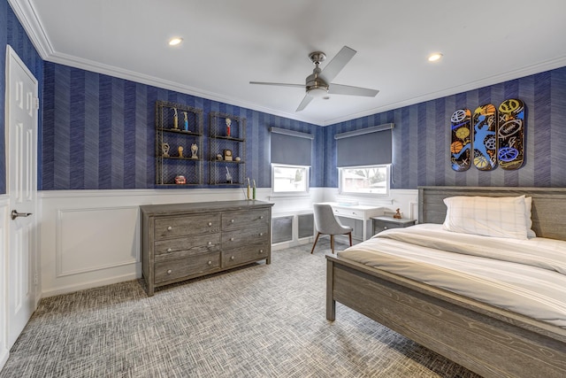 carpeted bedroom featuring a wainscoted wall, ornamental molding, built in desk, and wallpapered walls