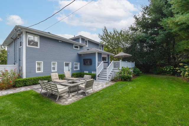 rear view of property with a deck, a patio, a fire pit, and a lawn