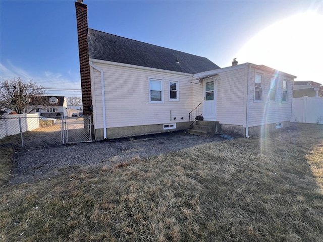 rear view of house with a gate, entry steps, fence, roof with shingles, and a chimney