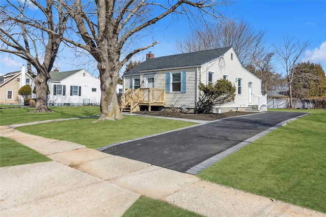 bungalow-style house with driveway, a chimney, a front lawn, and a shingled roof