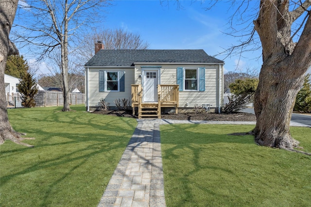 bungalow-style house featuring a chimney, a shingled roof, a front lawn, and fence