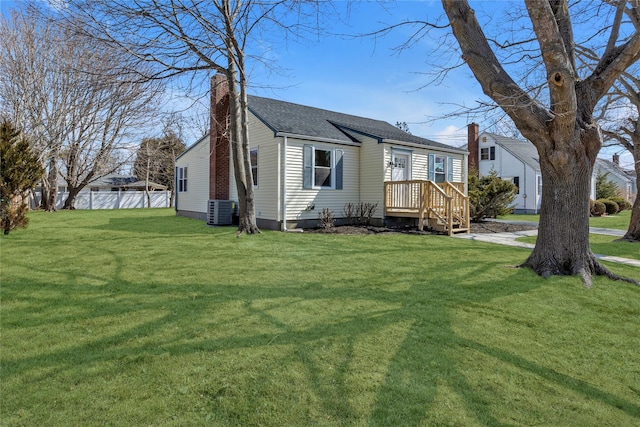 view of front of property with a front lawn, fence, a shingled roof, central AC unit, and a chimney