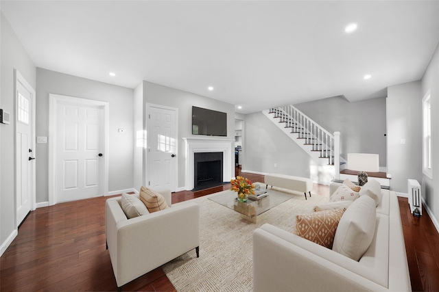 living area with recessed lighting, dark wood-style flooring, stairs, and radiator heating unit