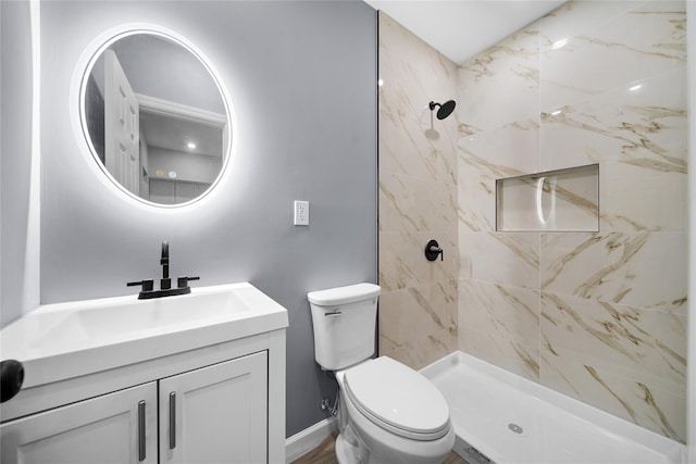 full bathroom featuring vanity, toilet, baseboards, and tiled shower