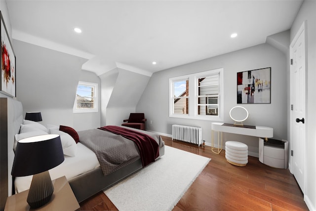 bedroom with radiator, wood finished floors, baseboards, lofted ceiling, and recessed lighting