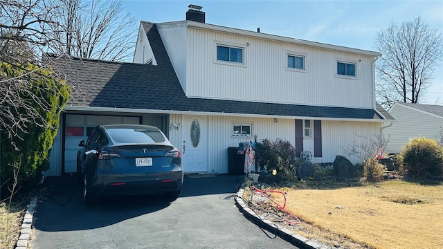 view of front facade with a shingled roof, aphalt driveway, and a chimney