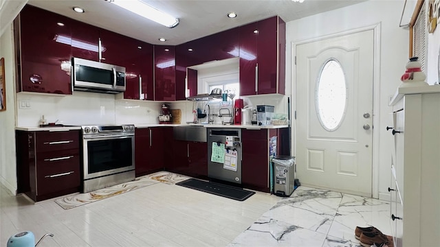 kitchen with a sink, stainless steel appliances, marble finish floor, and light countertops