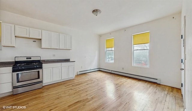 kitchen featuring light wood-style flooring, a baseboard heating unit, dark countertops, white cabinetry, and stainless steel range with gas cooktop