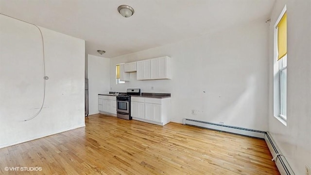 kitchen featuring light wood-type flooring, plenty of natural light, stainless steel range with gas cooktop, and white cabinetry