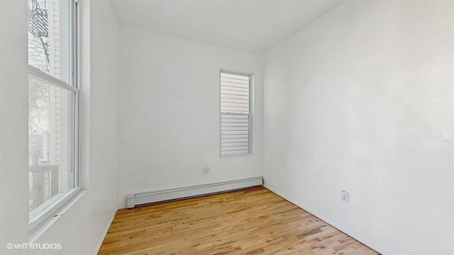 spare room featuring a baseboard heating unit and wood finished floors