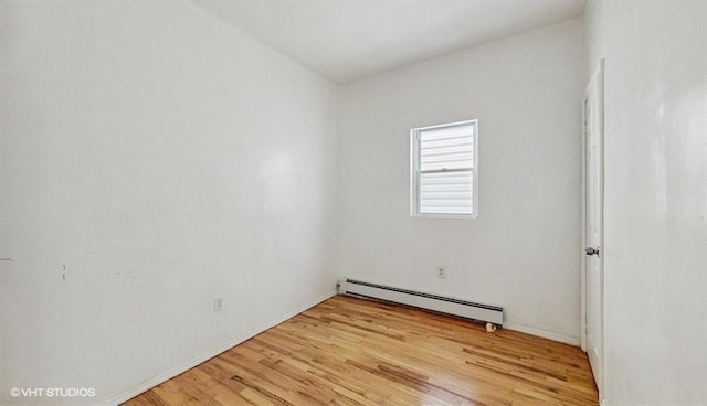 unfurnished room featuring light wood-type flooring and a baseboard heating unit