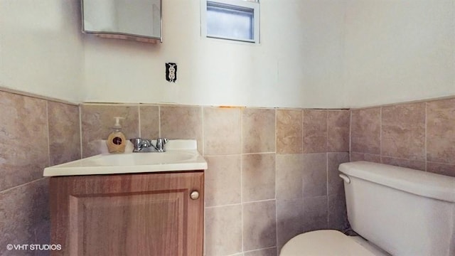 bathroom featuring vanity, tile walls, toilet, and wainscoting