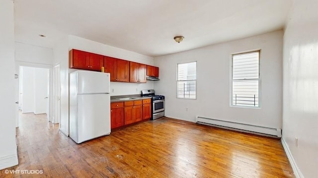 kitchen with stainless steel gas stove, light wood-style flooring, under cabinet range hood, a baseboard heating unit, and freestanding refrigerator