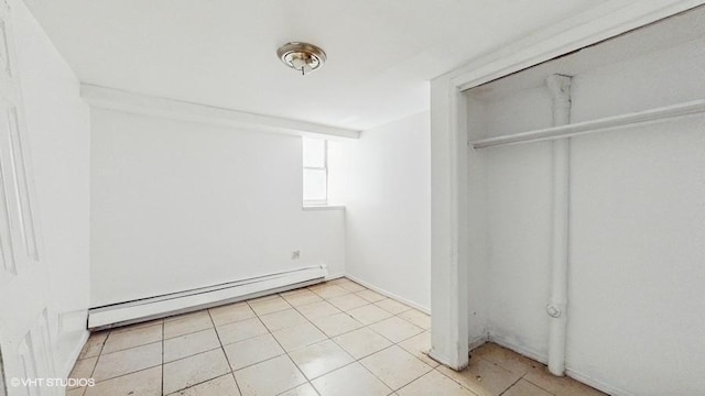 unfurnished bedroom featuring a closet, baseboard heating, and light tile patterned floors