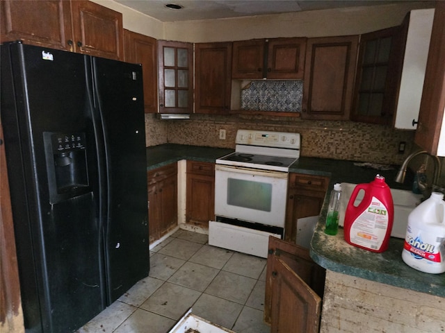 kitchen with light tile patterned floors, dark countertops, black fridge, and electric stove