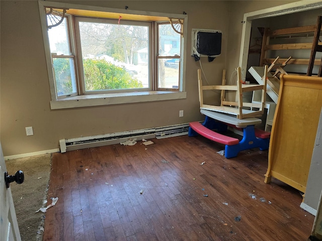 bedroom featuring a baseboard heating unit, baseboards, and wood-type flooring