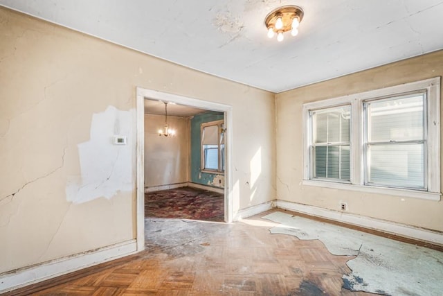 spare room featuring baseboards and a notable chandelier