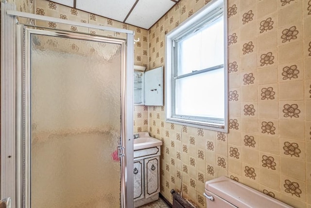 full bathroom featuring toilet, a stall shower, wallpapered walls, and vanity