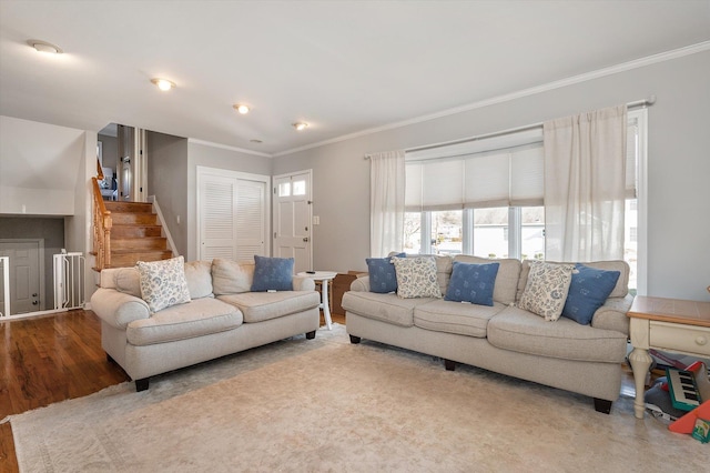 living area featuring wood finished floors, stairs, and crown molding