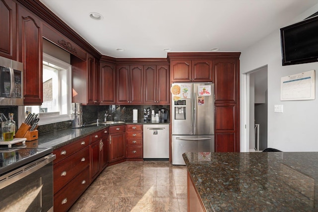 kitchen with dark stone counters, a sink, decorative backsplash, stainless steel appliances, and dark brown cabinets