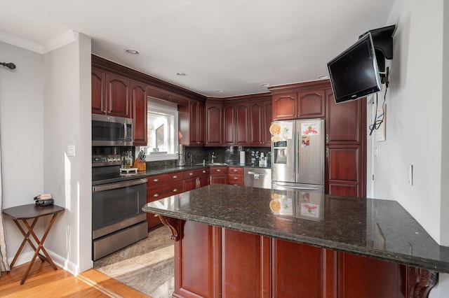 kitchen featuring dark stone countertops, backsplash, stainless steel appliances, crown molding, and dark brown cabinets