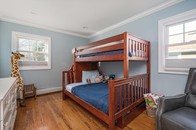 bedroom featuring wood finished floors, a baseboard heating unit, and ornamental molding