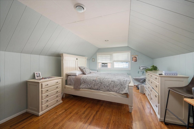 bedroom with vaulted ceiling, cooling unit, and light wood finished floors