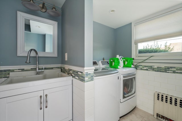 laundry area with washing machine and dryer, radiator heating unit, laundry area, tile walls, and a sink