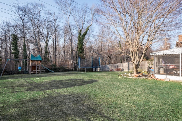 view of yard featuring a playground, a trampoline, a fenced backyard, and a sunroom