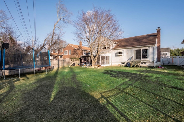 view of yard with entry steps, a trampoline, and a fenced backyard