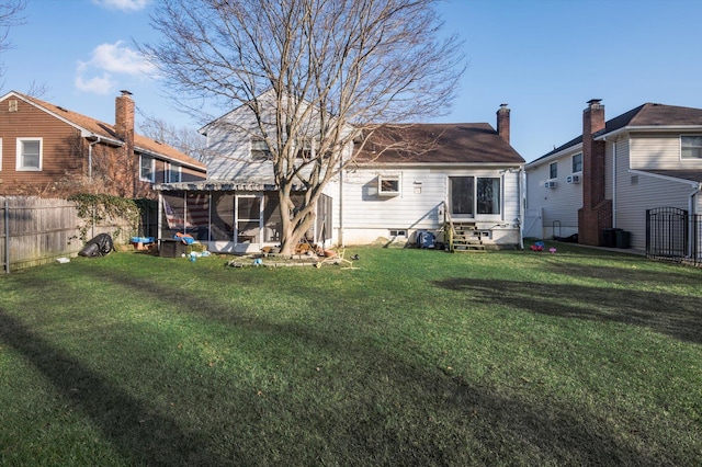 rear view of property with a yard, entry steps, a chimney, and a fenced backyard