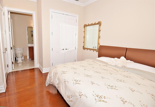 bedroom featuring ornamental molding, wood finished floors, connected bathroom, a closet, and baseboards