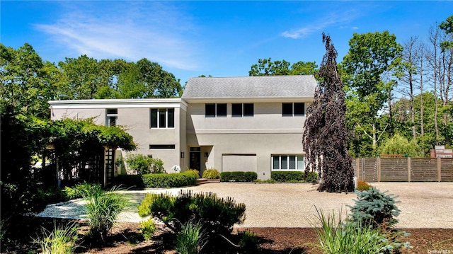 view of front facade with fence and stucco siding