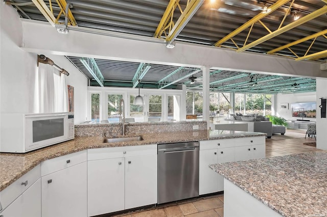 kitchen with dishwasher, white microwave, white cabinetry, and a sink