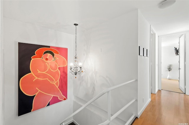 hall featuring a chandelier, baseboards, and wood finished floors