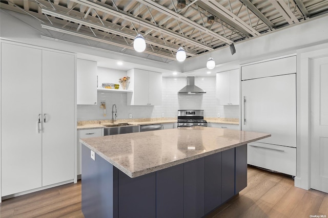 kitchen featuring open shelves, a sink, stainless steel appliances, light wood-style floors, and wall chimney exhaust hood