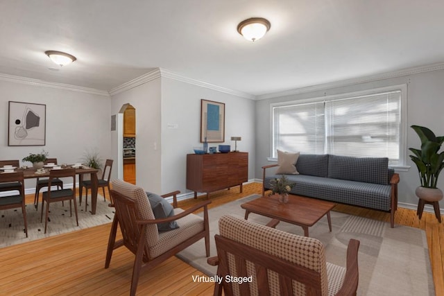 living area with arched walkways, crown molding, light wood-type flooring, and baseboards