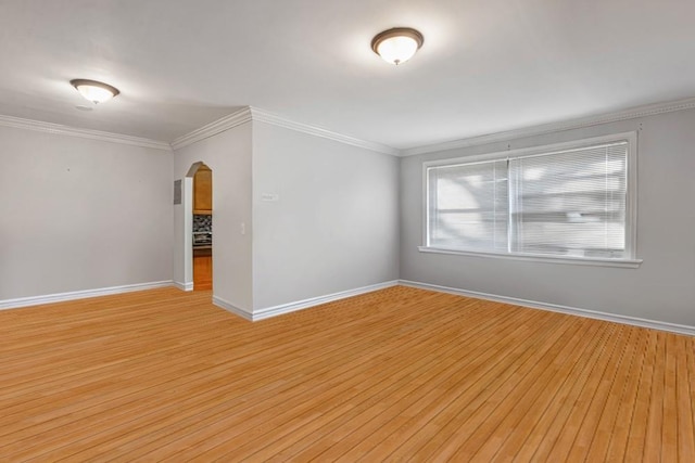 empty room with light wood-type flooring, arched walkways, baseboards, and ornamental molding