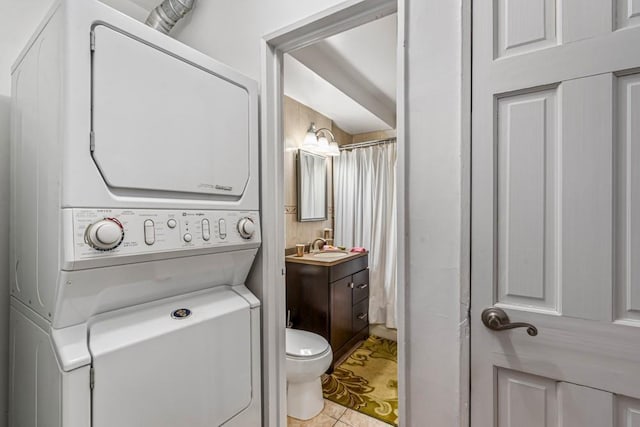 full bath with tile patterned flooring, stacked washer / dryer, toilet, and vanity