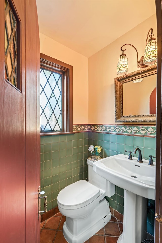 half bath with tile patterned flooring, tile walls, toilet, and wainscoting