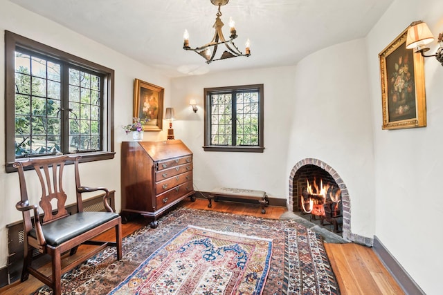 sitting room with a wealth of natural light, baseboards, an inviting chandelier, and wood finished floors