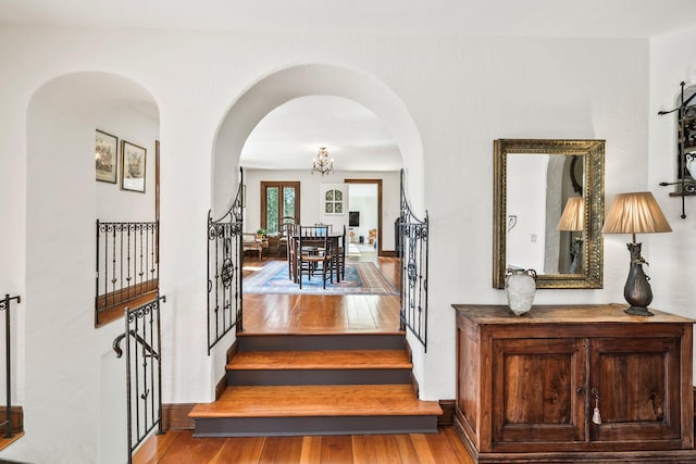 foyer with arched walkways, stairs, and hardwood / wood-style flooring