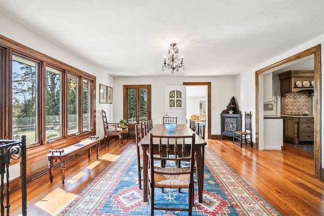 dining space with a wood stove, a notable chandelier, wood finished floors, and baseboards