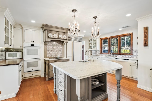 kitchen featuring white appliances, wood finished floors, visible vents, an inviting chandelier, and a sink