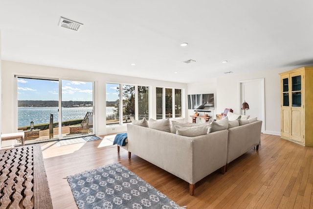 living area with recessed lighting, visible vents, a water view, and light wood finished floors