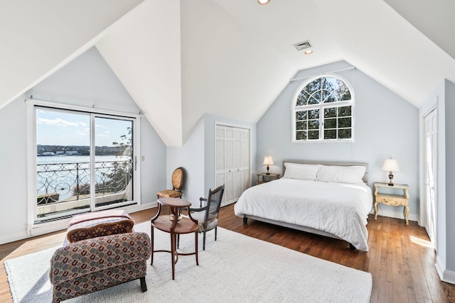 bedroom with visible vents, multiple windows, lofted ceiling, and wood finished floors