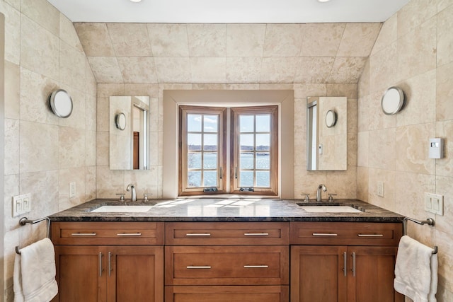 full bath featuring double vanity, tile walls, and a sink