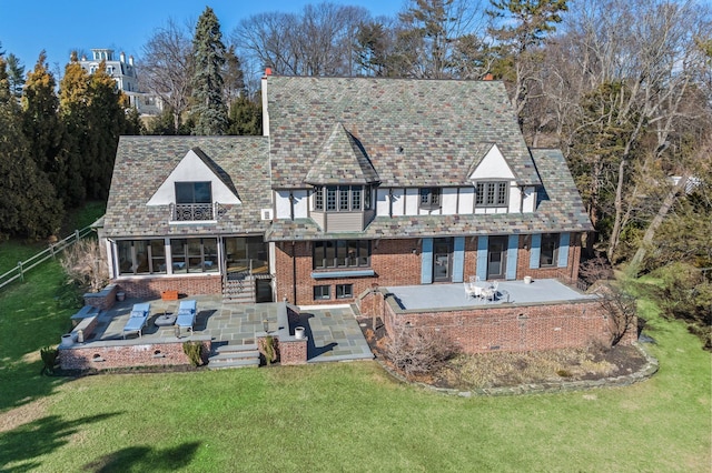 back of house featuring a yard, a patio area, and brick siding