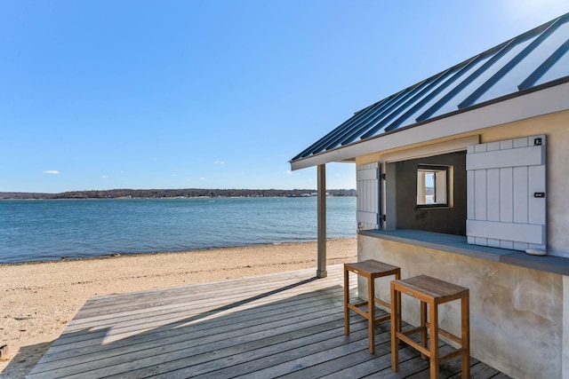 view of dock with a deck with water view, a beach view, and outdoor dry bar